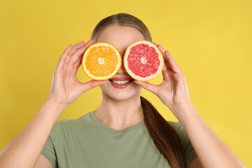 Sticker - Young woman with cut orange and grapefruit on yellow background. Vitamin rich food