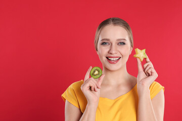 Sticker - Young woman with cut kiwi and carambola on red background, space for text. Vitamin rich food