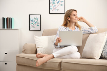 Sticker - Pretty young woman with laptop sitting on sofa at home