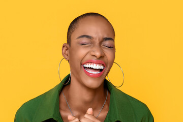 Wall Mural - Close up portrait of happy  African American woman laughing with eyes closed in isolated studio yellow background