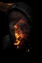 Halloween Creepy Man In Shadow With Hood And Burning Fire Portrait. Demon Possession With Glowing Red Eyes From Hell Concept