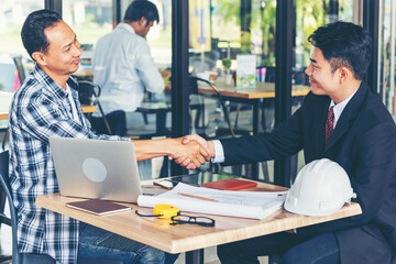 Diversity two business partners shaking hands together with business contract mergers and acquisitions. Close up honest hands business teams handshaking at office desk. Trust partnership shaking hands