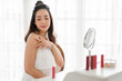 © Art_Photo - Smiling of young beautiful asian woman clean fresh healthy white skin looking at mirror.girl touching on her arm with hand and applying cream at home.spa and beauty concept