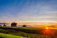 Old Weathered Barn And Weather Vane On A Corn Field As The Sunburst Is Seen At Sunset
