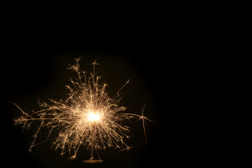 Christmas and New Year party sparkler on black burning colored sparkler on a black background, copy space