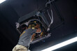 Worker repairing a ceiling air conditioning unit (Cleaning air-conditioner)