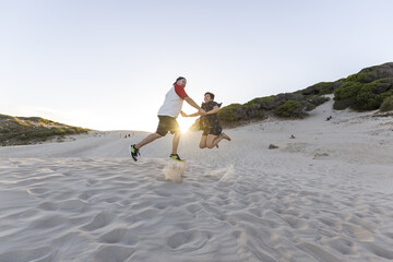 Poster - Young cheerful couple having fun on the beach at sunset