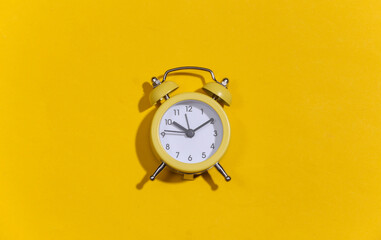 Wall Mural - Yellow retro alarm clock on a yellow bright background. Top view. Minimalism