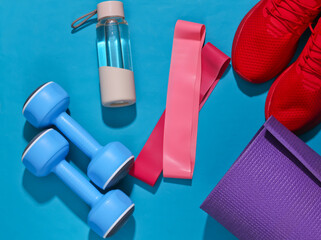 Wall Mural - Flat lay fitness composition. Sports equipment on a bright blue background with deep shadow. Top view