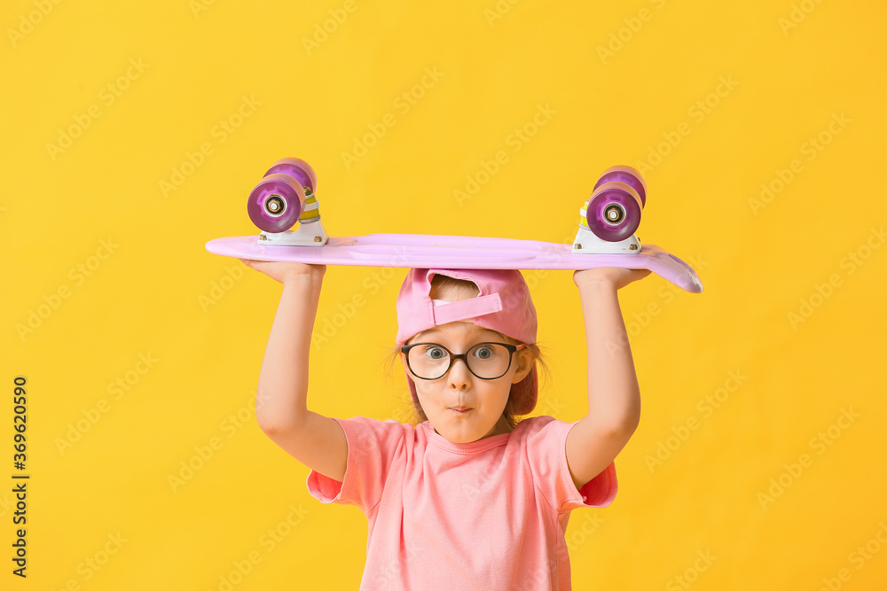 Cute little girl with skateboard on color background
