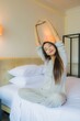 © siraphol - Portrait beautiful young asian woman smile happy relax on bed
