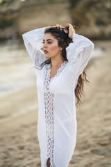 Canvas Print - Vertical shot a young European female wearing a white dress standing on the seashore