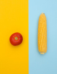 Swing of corn, tomato on blue yellow background. Minimalism food flat lay. Top view