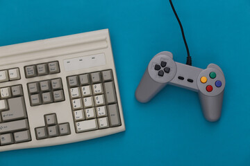 Wall Mural - Old keyboard and old-fashioned gamepad on a blue background. Retro gaming. 80s. Top view. Flat lay