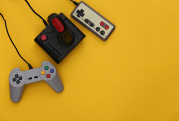 Wall Mural - Set of different retro gamepads and joysticks on a yellow background. Video game. Flat lay, top view, copy space