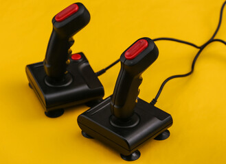 Wall Mural - Two retro joysticks on yellow background. Gaming, video game competition.