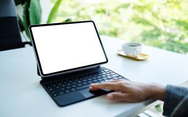 Mockup image of a woman touching on tablet touchpad with blank white desktop screen as computer pc in the office