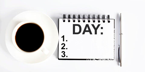 Poster - DAY , planning concept. Spiral notebook with text on white background with coffee