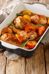 Wall Mural - Summer food chicken legs baked in with fresh plums and rosemary close-up in a baking dish on the table. vertical