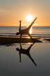 Silhouette of woman practicing the half moon bow variation yoga on the beach at morning sunset scene. Sugarcane pose yoga. (Ardha Chandrasana Pose) 