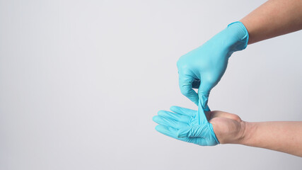 Hand is remove blue surgical gloves by peel the glove away from your body on white background.