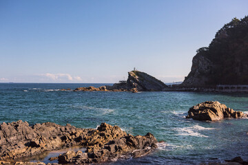 the huge waves crashing into ston island against the blue sky and horizon at summer sea shore.