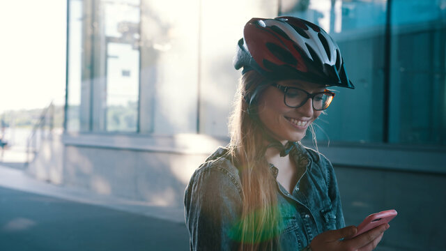 Happy caucasian woman with helmet rollerblading through the city and checking the app on the smartphone. High quality photo