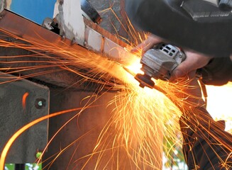 Worker cuts car metal by angular grinding machine