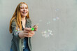 © Drobot Dean - Smiling girl blowing bubbles over wall