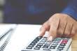 © methaphum - Close up business man hand using calculator counting making Calculate the cost of checking documents income and tax notes accounting at doing finance in office. Savings finances concept. note pad