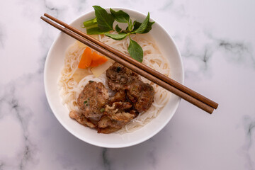 Sticker - High angle shot of an Asian dish with noodles and meat, with chopsticks on a marble surface