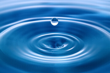  Water droplets fall down closely into the dark blue water, making it the perfect center in nature.