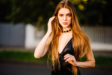 portrait of beautiful young girl in black dress outdoors, attractive woman with long hair