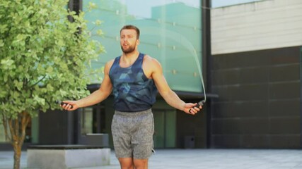 Poster - fitness, sport and exercising concept - man skipping with jump rope outdoors