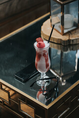 Poster - Vertical shot of a glass of strawberry smoothie on a table in a restaurant