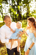 © shunevich - Lovely young family walking at the park, caring parents play with little daughter, hugging and smiling, loving dad hold adorable baby girl in arms, enjoy weekend outdoors, parenthood concept