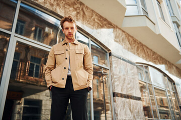 Wall Mural - Elegant young man in formal classy clothes outdoors in the city near building