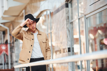 Canvas Print - Elegant young man in black hat and formal classy clothes outdoors in the city