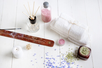 Beautiful spa composition on massage table in wellness center, copyspace. Accessories for relaxing treatments and personal care. Towels, oils, serum, sea salts and scrubs. Decorative candles. Top view