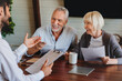 © InsideCreativeHouse - Happy aged couple consulting with insurance agent at home
