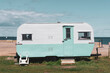 Camping on the beach in a vintage turquoise and white caravan trailer.