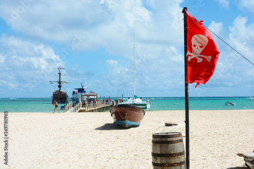Fotografía Pirate brig at pier on sandy beach with pirate flag