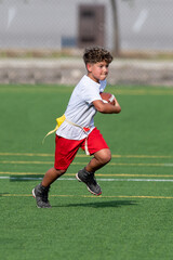 Wall Mural - Cute athletic little boy playing excitedly in a flag football game