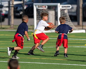 Wall Mural - Cute athletic little boy playing excitedly in a flag football game