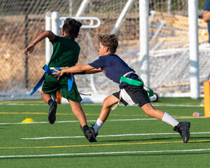 Wall Mural - Young athletic boy playing in a flag football game