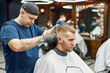 © Svitlana - Side view of a young handsome man visiting barbershop and getting new trendy haircut. Barber working with hair clipper. Focus on a head