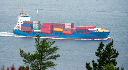 Cargo freight ship with lots of cargo containers sailing on sea.