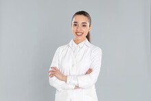 Happy Young Woman In Lab Coat On Light Grey Background