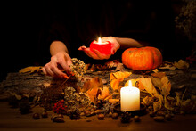 Forest Witch At Work On The Altar. Female Hands With Sharp Red Nails Among Candles, Herbs, Pumpkin, Nuts, Dry Leaves, Acorns, Ashberry, Selected Focus, Low Key