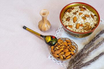 Khohloma bowl and spoon with oatmeal, raisins, nuts and seeds. Healthy  breakfast concept on beige linen background. Flatlay.